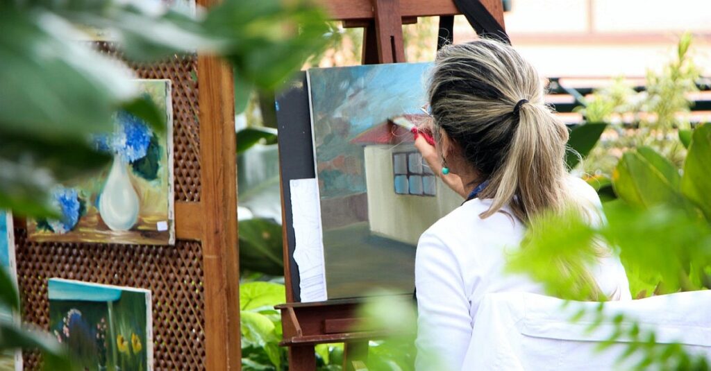 Artystka malująca obraz prezentujący dom.